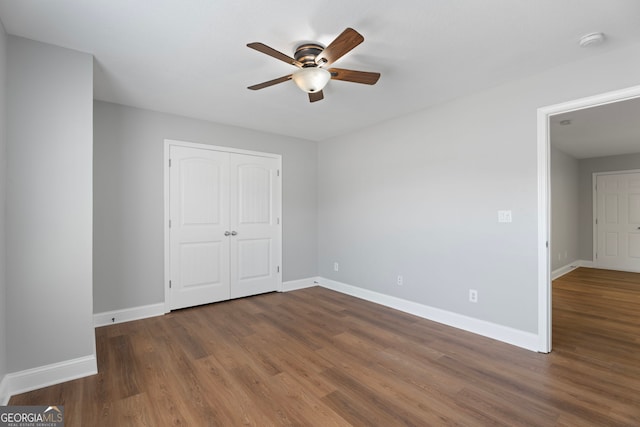 unfurnished bedroom with ceiling fan, a closet, wood finished floors, and baseboards