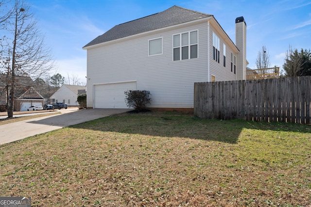 view of home's exterior with a yard, a chimney, fence, a garage, and driveway