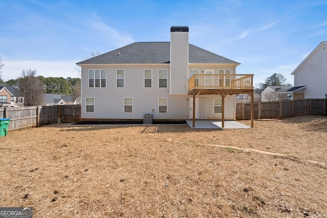 back of property with a fenced backyard, a chimney, central AC unit, and a patio