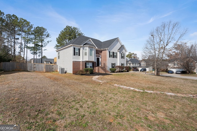 view of front of property with cooling unit, brick siding, fence, and a front yard