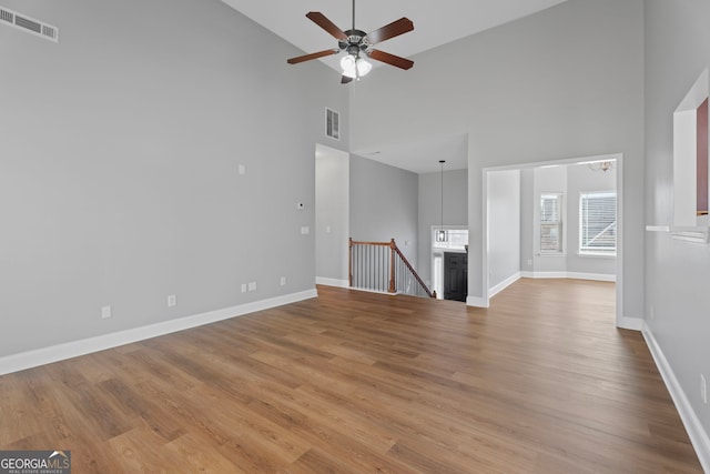 unfurnished living room featuring visible vents, baseboards, and wood finished floors