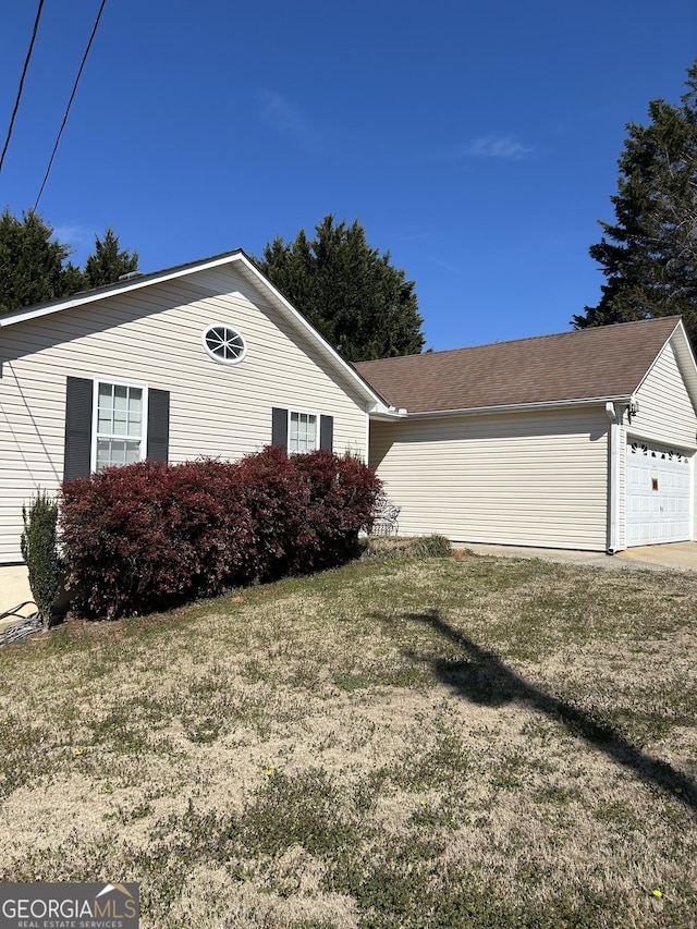 view of side of property featuring a garage and a yard