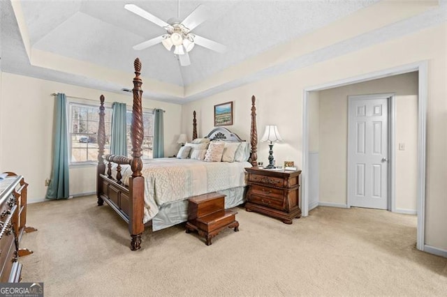 bedroom with light carpet, ceiling fan, baseboards, and a raised ceiling