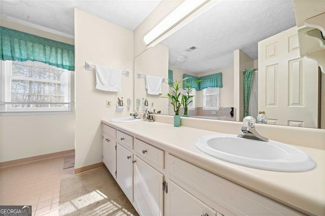 full bathroom with a textured ceiling, a sink, visible vents, and baseboards