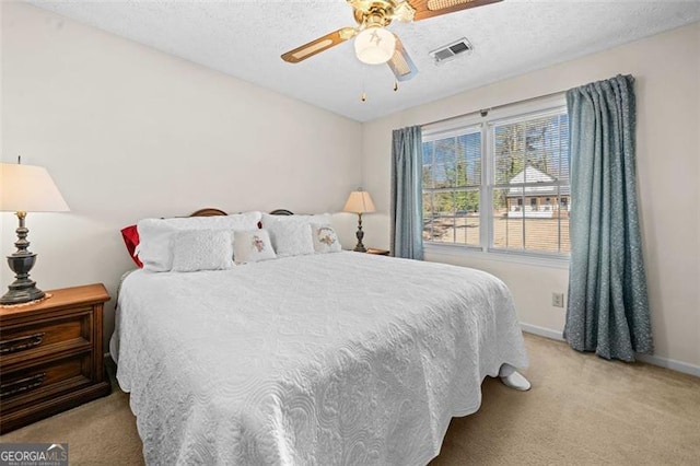 bedroom with a textured ceiling, carpet, visible vents, and baseboards