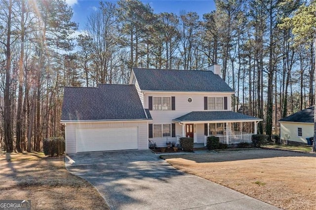 view of front of house with driveway, a chimney, roof with shingles, an attached garage, and covered porch