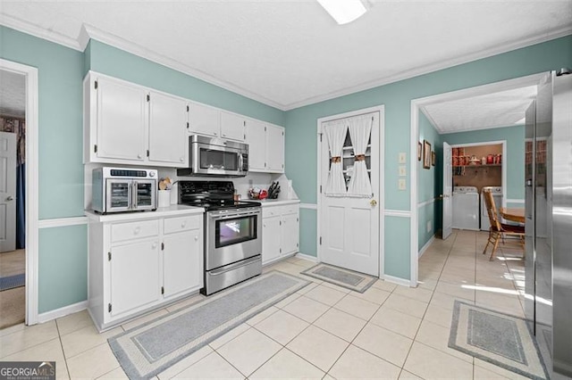 kitchen featuring appliances with stainless steel finishes, ornamental molding, washer and dryer, white cabinetry, and light tile patterned flooring