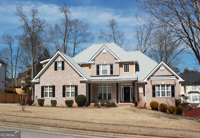 view of front of home with brick siding, a front yard, and fence