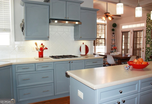 kitchen featuring pendant lighting, light countertops, white gas cooktop, blue cabinets, and under cabinet range hood