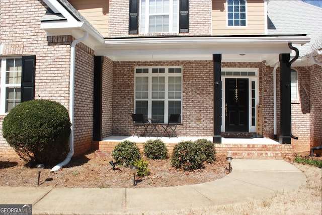 property entrance featuring a porch and brick siding