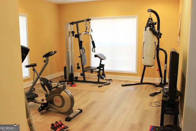 workout area featuring wood finished floors, a wealth of natural light, and baseboards