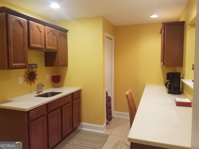 kitchen featuring light tile patterned floors, baseboards, light countertops, and a sink