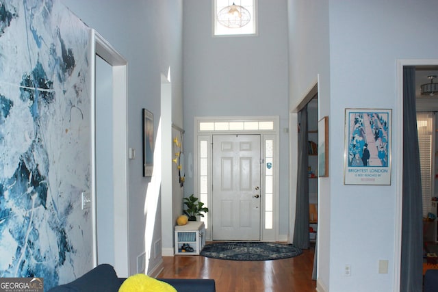 entrance foyer featuring visible vents, a high ceiling, and wood finished floors