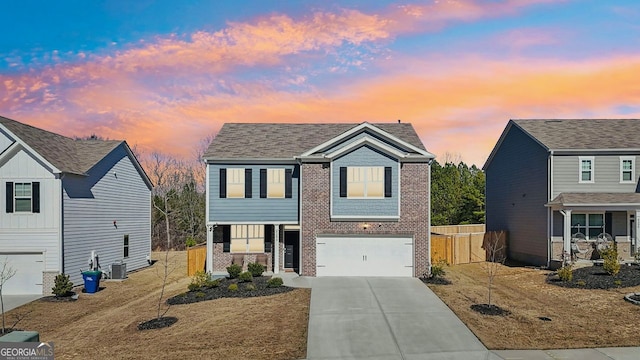 view of front of home with concrete driveway, an attached garage, fence, central air condition unit, and brick siding