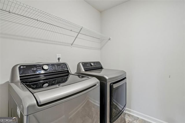 washroom with washing machine and dryer, laundry area, and baseboards