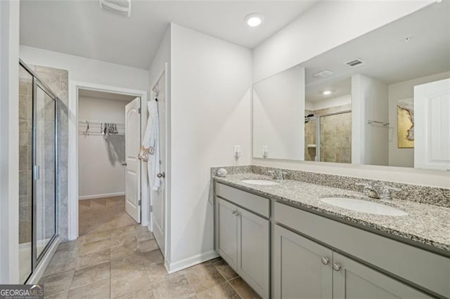 full bathroom featuring a stall shower, a walk in closet, a sink, and double vanity