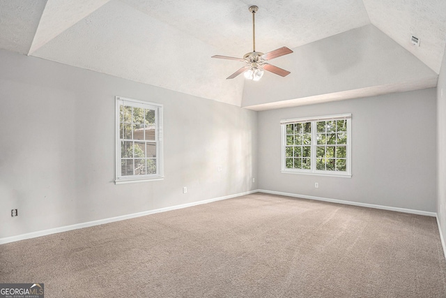 empty room featuring lofted ceiling, a textured ceiling, a ceiling fan, baseboards, and carpet