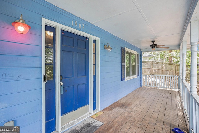 view of exterior entry with a garage, ceiling fan, and a porch