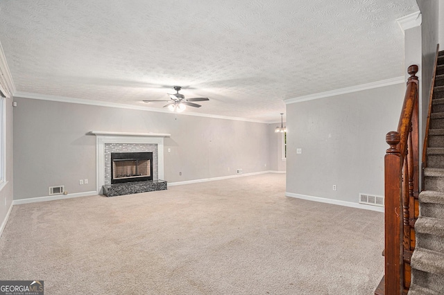 unfurnished living room with stairway, ceiling fan, visible vents, and a fireplace with raised hearth