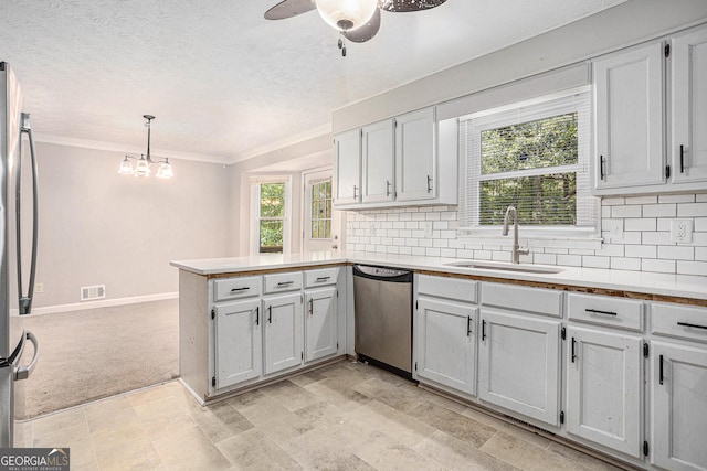 kitchen with a peninsula, tasteful backsplash, appliances with stainless steel finishes, and a sink