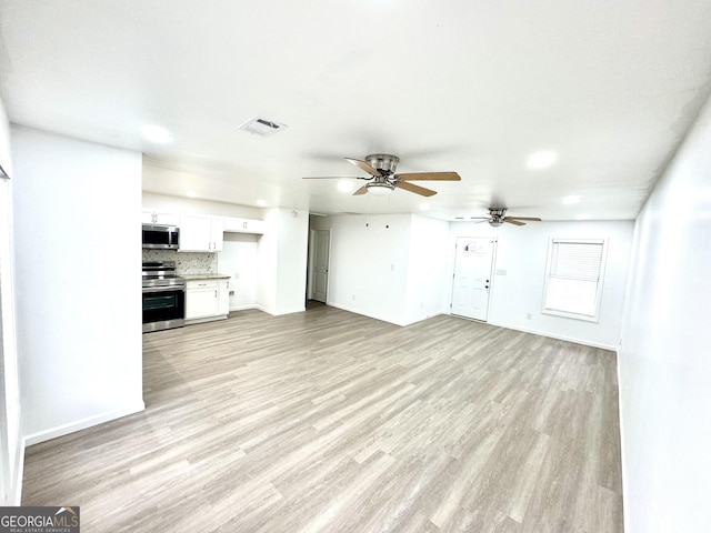 unfurnished living room with ceiling fan, light wood finished floors, visible vents, and baseboards