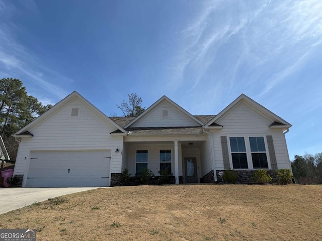 view of front of home featuring a garage, driveway, stone siding, and a front yard