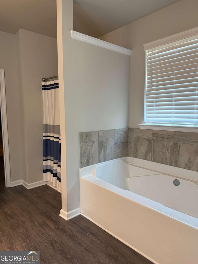 full bath featuring curtained shower, wood finished floors, a bath, and baseboards