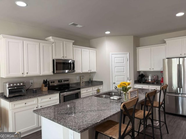 kitchen with white cabinets, stainless steel appliances, a sink, and a kitchen breakfast bar