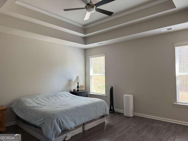 bedroom featuring visible vents, baseboards, a raised ceiling, dark wood-style floors, and crown molding