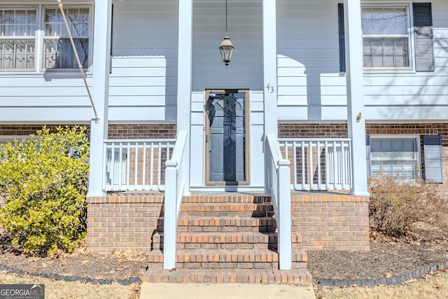 property entrance featuring a porch and brick siding