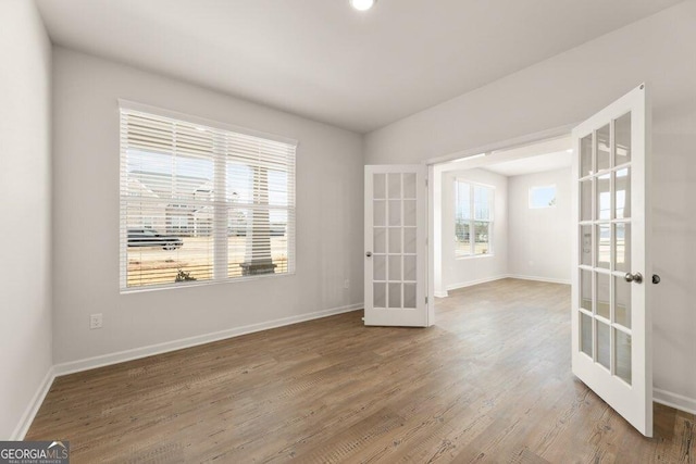 spare room with french doors, wood finished floors, and baseboards