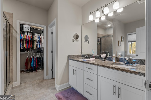 bathroom featuring a stall shower, a sink, a spacious closet, and double vanity