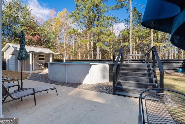 view of patio featuring an outdoor structure, fence, a detached garage, and an outdoor pool