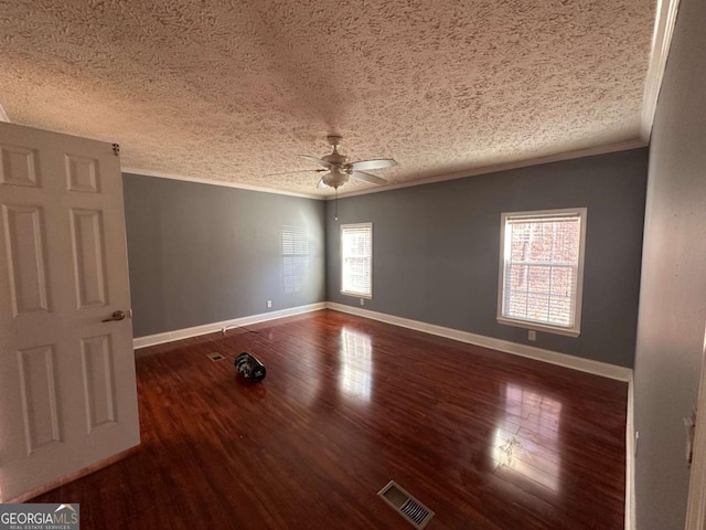 spare room featuring baseboards, visible vents, wood finished floors, a textured ceiling, and crown molding