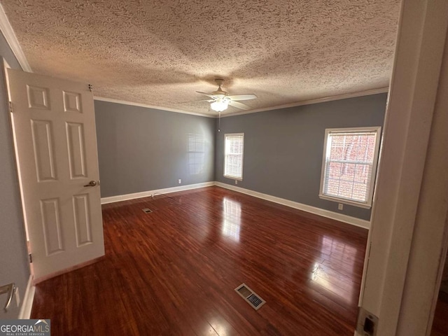 spare room with ceiling fan, visible vents, dark wood-style flooring, and ornamental molding