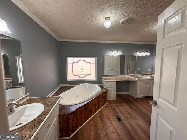 bathroom featuring a garden tub, wood finished floors, two vanities, and a sink