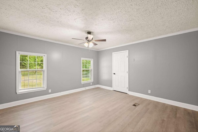 unfurnished room featuring ceiling fan, a textured ceiling, wood finished floors, baseboards, and crown molding