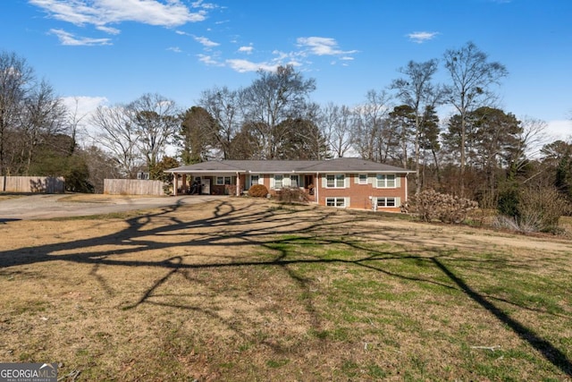 view of front of house with brick siding, a front yard, and fence