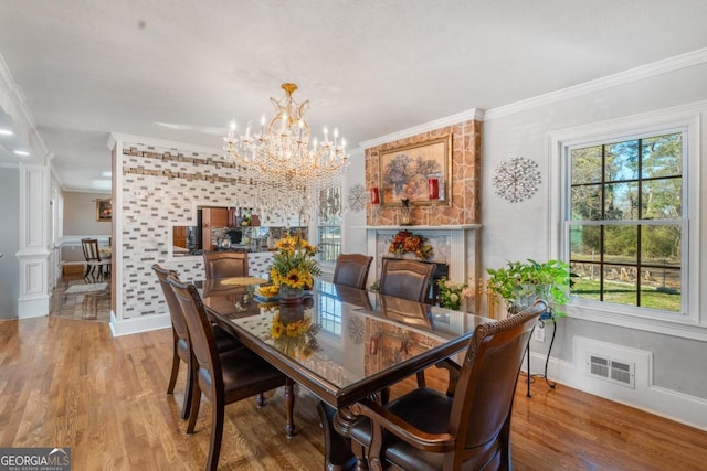 dining space featuring light wood-style flooring, visible vents, a chandelier, and crown molding