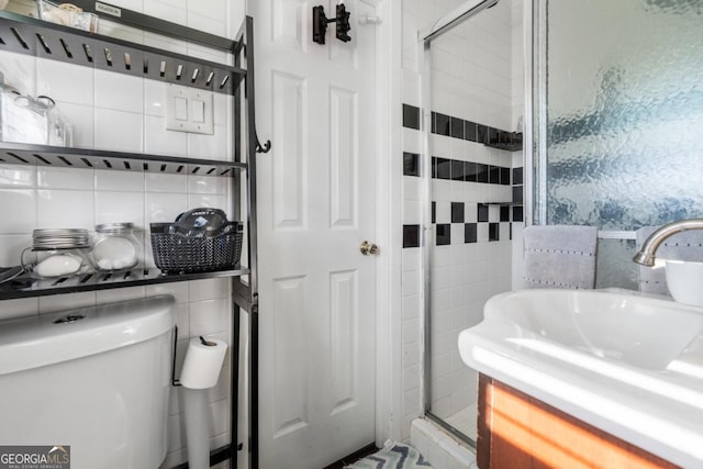 bathroom with a sink, a shower stall, toilet, and tile walls