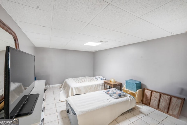 bedroom featuring light tile patterned floors, a paneled ceiling, and baseboards