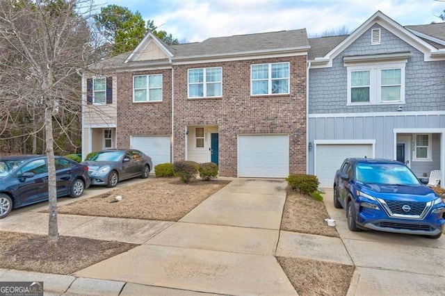 multi unit property featuring a garage, driveway, brick siding, and board and batten siding