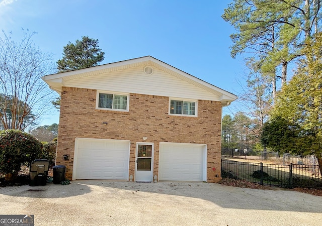 view of home's exterior featuring a garage, brick siding, fence, and driveway