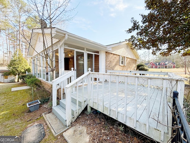 exterior space with a sunroom, brick siding, and a wooden deck