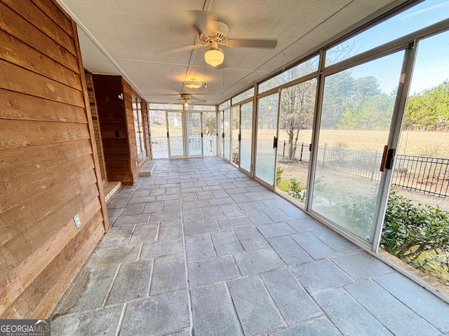 unfurnished sunroom featuring a ceiling fan