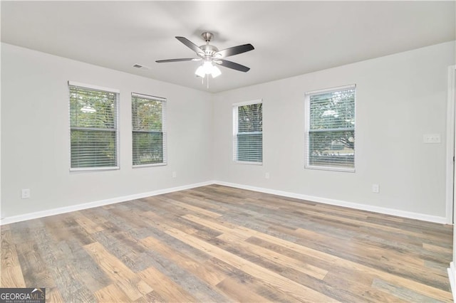 empty room with baseboards, wood finished floors, visible vents, and ceiling fan