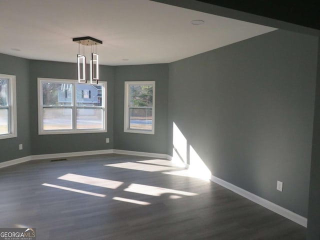 unfurnished dining area with dark wood-type flooring and baseboards