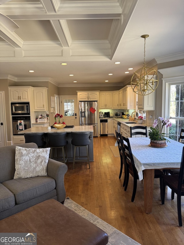 dining space with coffered ceiling, wood finished floors, crown molding, a chandelier, and recessed lighting