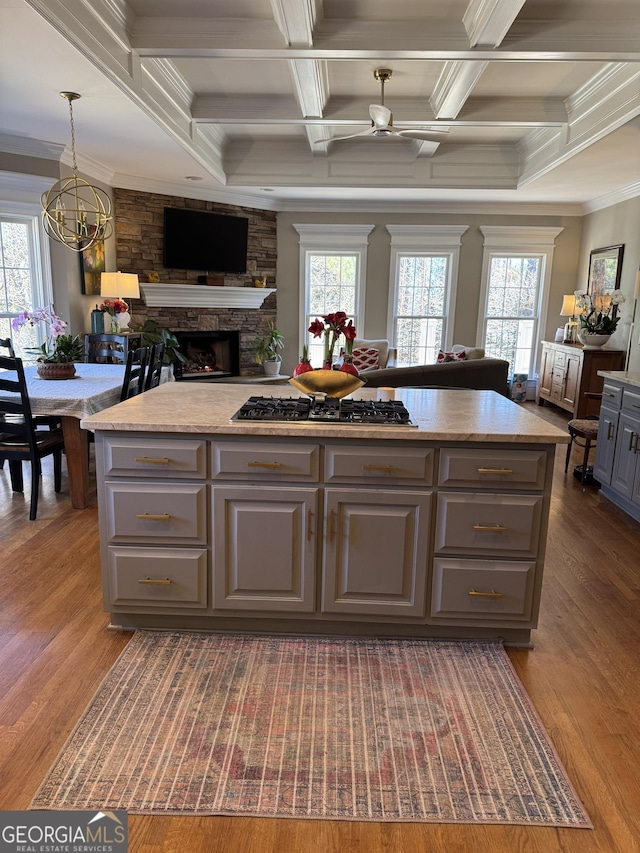 kitchen with gray cabinetry, a kitchen island, wood finished floors, open floor plan, and stainless steel gas stovetop