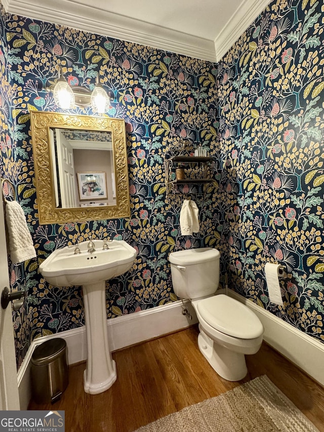 half bath with wallpapered walls, wood finished floors, toilet, and crown molding